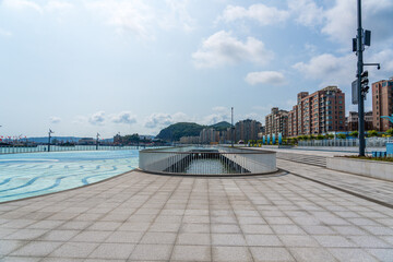 Fototapeta premium Serene Waterfront Scene with Modern Architecture and Scenic Mountains