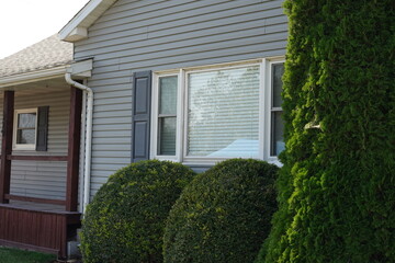 house with light gray siding and a large front window with white trim and closed blinds