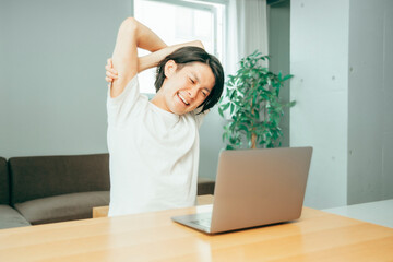 ノートパソコンの前でストレッチする男性
