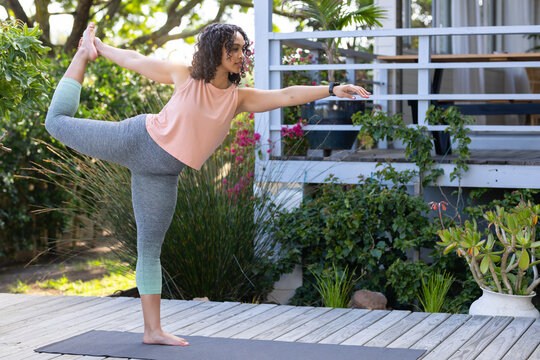 Woman practicing yoga on mat outdoors, balancing gracefully in nature