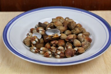 Fresh steamed clams, boiled clams served on a white plate with an easy seafood recipe menu, blood clams