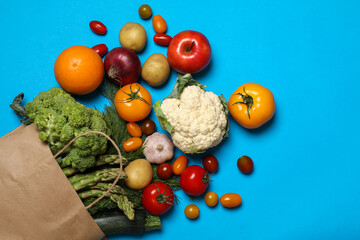 Delivery of vegetarian products. Bag with different vegetables and fruits on light blue background, top view