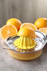 Juicer and oranges on grey table, closeup