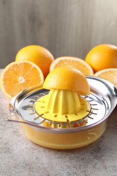 Juicer and oranges on grey table, closeup