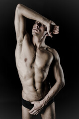 Young attractive man with athletic body posing in studio.