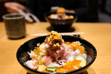 Two bowls of chirashi-don with sushi rice, sashimi off-cuts, salmon roe, sea urchin and fresh vegetables (onion and cucumber) at Sushi Tokyo Ten, a restaurant in Shinjuku — Tokyo, Japan