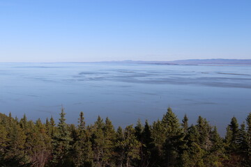 A beautiful view from above on a large river in autumn. Autumn background with a coastline, island, and blue sky. September or october calendar. A scenic view of the St-laurent river from Charlevoix.