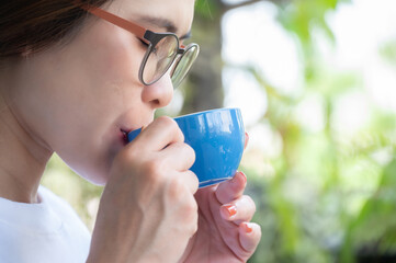 Portrait of Asian woman smelling coffee scent before drinking. The aroma of coffee is...