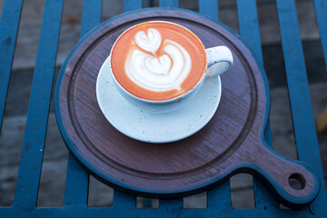 Thai tea mixed with milk in latte glass on wood table. Space for text. Close up. Top view of hot Thai tea latte with latte art.