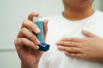 Asthma and chronic obstructive pulmonary disease COPD, Asian young man using metered dose inhaler...