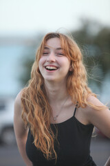 portrait of cheerful teenage girl outdoors at dusk with ocean and sky in background