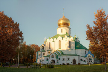 Feodorovskiy Gosudarev Sobor illuminated by sunset light, with a large oak tree featuring golden...