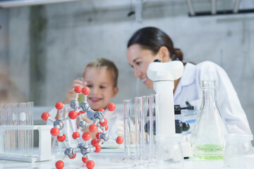 Smiling woman and child boy in lab coats working with molecular model, Science kids modern...