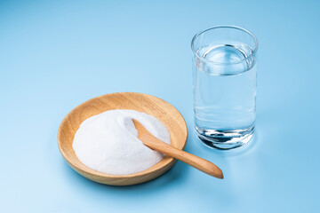 水色背景に木の器にはいった重曹とコップの水
