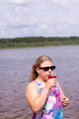 On a hot summer day, a child is relaxing on the lake. A girl on the beach. The girl drinks delicious fresh juice.