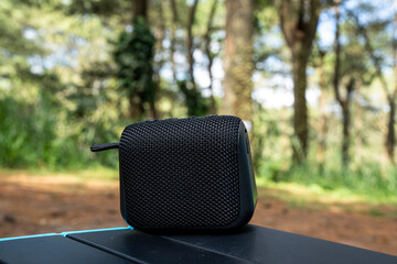 a bluetooth speaker on the table with forest background while camping
