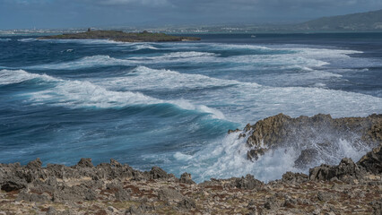 The ocean waves are raging in the strait between the rocky islands. Foam, splashes on volcanic rocks. Mauritius. Île au Phare 