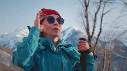 Portrait: an old gray-haired woman hiking in the winter mountains. The senior female uses sticks for Nordic walking. Hiking to the Snowy peaks in the national Park. Elderly Granny's Face, hiking.