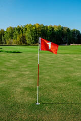 Obraz premium A Beautiful and Serene Scene Depicting a Tranquil Golf Course with a Bright Flag at Its Peak
