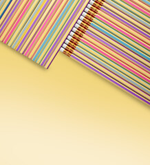 Colorful pencils arranged in diagonal composition on pastel yellow background.