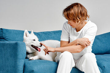 Woman Touching Husky's Nose on Blue Sofa