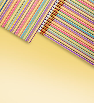 Colorful pencils arranged in diagonal composition on pastel yellow background.