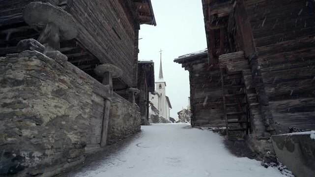 An old village in the Swiss mountains, Blatten bei Naters in winter with heavy snowfall and blizzard - static shot