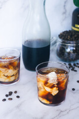 a glass of homemade iced cold brew coffee with milk on white marble table.