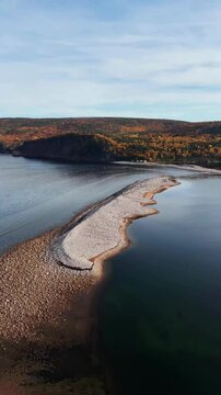 Ingonish Beach along Cabot Trail, Cape Breton, Nova Scotia, Canada. Incredible blue ocean waters with  the autumn fall foliage colors. [Vertical Video]