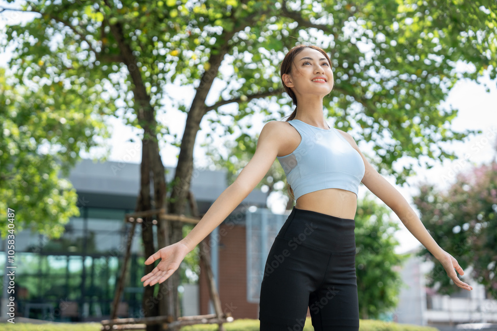 Wall mural healthy and fit asian woman wearing sportswear warming up in the park at sunrise. confident young fe