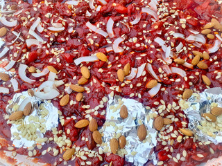 Red fresh jam food with white sesame seeds, coconut slices, unpeel almond nuts and dates full frame background