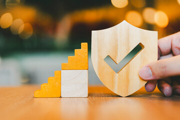 Insurance salesman holding shield symbol with wooden ladder step by step. Concept of insurance...