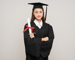 Happy asian woman in graduation costume with cap holding diploma on isolated background. College...