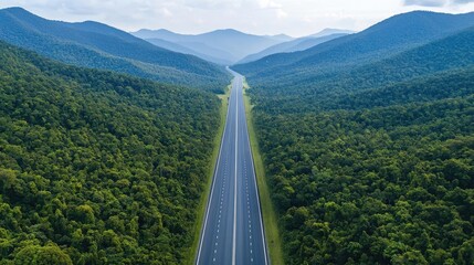 Scenic highway through lush mountains and green forests under a clear blue sky.