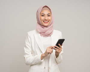 Portrait happy young asian business muslim woman holding smartphone standing on isolated white...