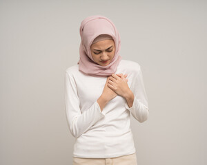 Unhealthy young asian muslim woman felt a pain chest held hand and squeezed it. Heart attack that needs treatment on isolated white background. Muslim woman wearing abaya and hijab costume