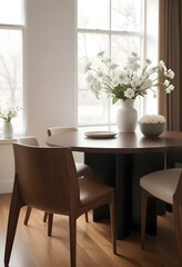 A cozy dining room with a wooden table and chairs, a vase of white flowers, and a framed artwork on the wall.