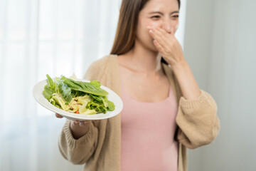 Unhappy young asian pregnant woman feeling with morning sickness to vegetable salad, frustrated...