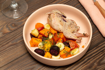 A portion of baked root vegetables, sweet potatoes, carrots with quail