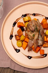 A portion of baked root vegetables, sweet potatoes, carrots, white, yellow, orange, blue with quail