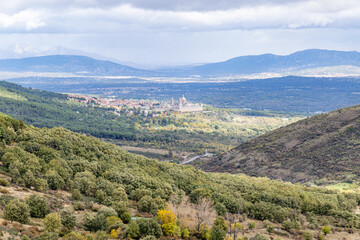 Obraz premium Royal Monastery of San Lorenzo de El Escorial, seen through the fog, from the Cruz Verde mountain pass