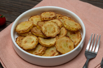 Slices of fried crookneck in oil with garlic on a wooden background