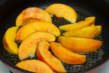 Frying peach slices in butter in a frying pan