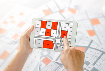 Woman holding a pencil pointing to cadastral map to decide to buy land. real estate concept with...