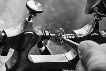 Watchmaker aligns a small cogwheel with precision tools in a vin