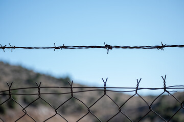 Barbed wire fence with blue sky at the background.