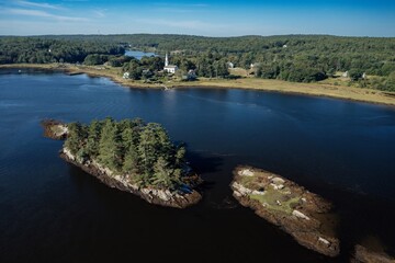 Island with trees and chursh in the distance on the Kennybec River, Phippsburg, Maine, United...