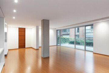 Obraz premium Spacious modern living area with hardwood floors and large windows in a residential building
