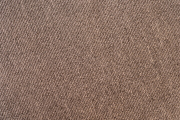 A gray-brown textured surface of a synthetic carpet with a close-up with rows of quilted knots with a diagonal slope to the right. Blank for the background in artworks.
