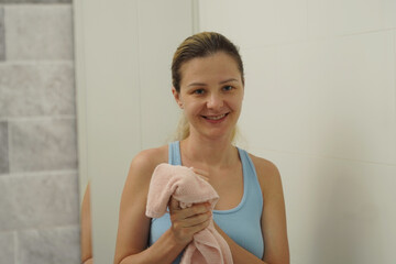  Young woman in a modern bathroom washing her face and brushing her teeth 